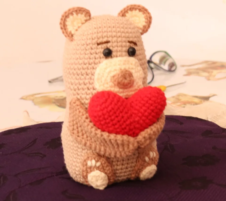 Osito amigurumi tejido a crochet sosteniendo un corazón rojo